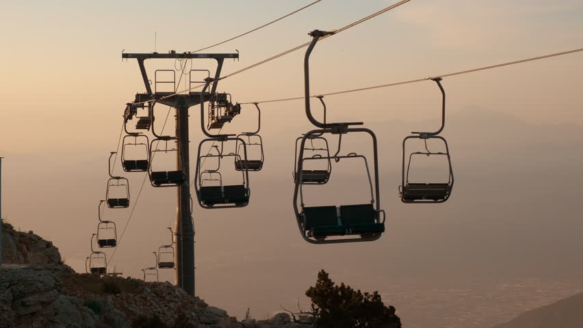 Empty cable cars against evening sky. A view of empty cable cars silhouettes against nightfall sky in summer. Royalty-Free Stock Footage #3391027013