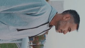 Vertical video, Middle-aged man in sportswear walks along bridge