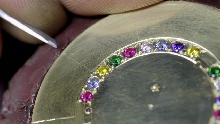 Hand Engraving lines into a golden pendant, fitted with colorful cristals, workshop 