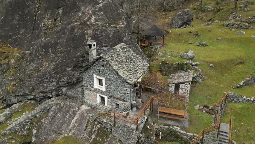 Aerial drone rotating shot over ruins of old stone walled houses in Cavergno village, District of Vallemaggia, Canton of Ticino, Switzerland on a cloudy day.