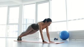 Useful exercises. Full length of adorable young woman doing push ups while being energetic and pleased