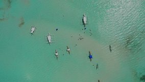 Aerial video of tour boats over a sand bar in Siargao Island, Philippines. Drone top view footage of people swimming in shallow turquoise sea waters on a bright sunny day. 