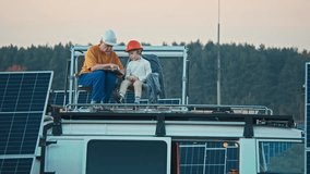 Camper van top roof near solar panels plant. Youngster with safety helmet and his grandpa. Using tablet. Energy education. New generation - Powered by Shutterstock - Get 15% off with code: PIKWIZARD15