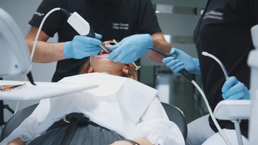 Odontology. Dental visit. Skillful doctor orthodontist with assistant doing professional dental treatment ultrasound modern brushing procedure of female's teeth. | Shutterstock HD Video #3391308887