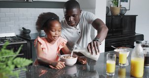 Video of african american father and daughter eating breakfast. Enjoying quality family time together at home.