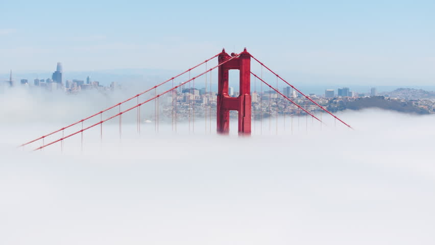 Cinematic dense thick fog with San Francisco on background. Flying above white cloudy fog around red pillar tower of Golden Gate Bridge. Aerial white clouds covering tall bridge on bright sunny day Royalty-Free Stock Footage #3391350201