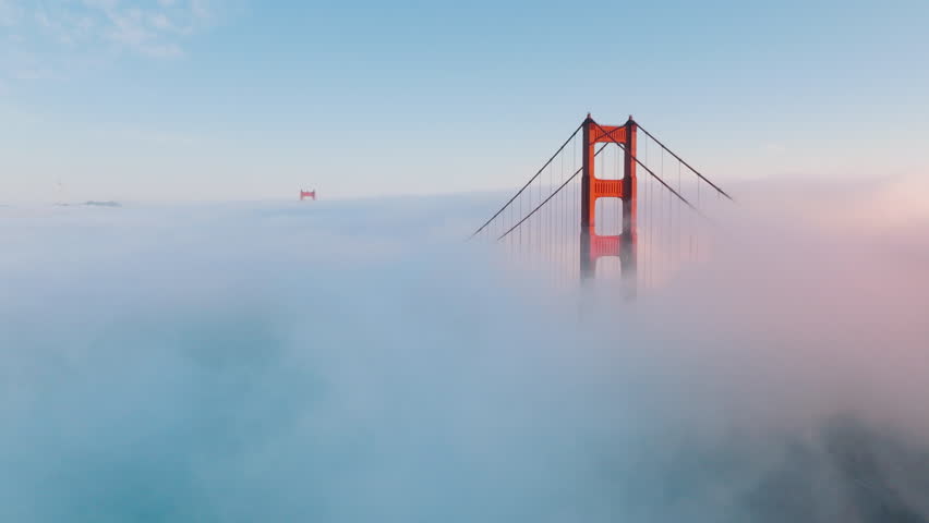 4K Cinematic shot of red top of the Golden Gate bridge seen above pastel cloudscape at sunset. Beautiful nature background. Aerial view over endless sea of pastel pink blue clouds until horizon USA Royalty-Free Stock Footage #3391352917