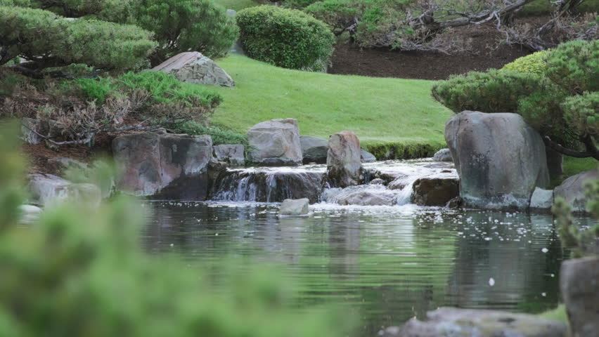 Small waterfall between the rocks in the Japanese Gardens. Slow motion.