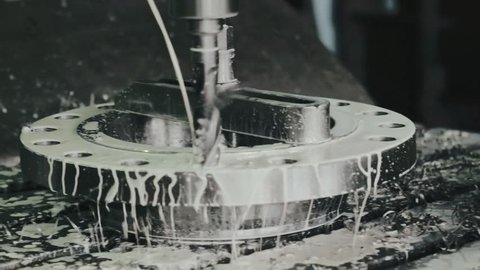 White lubricating and cooling liquid pouring on detail while drilling technical hole on modern turning lathe at production hall on metalworking industry