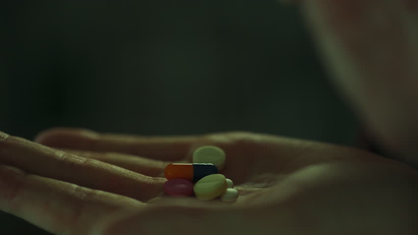 Antiviral agent. A patient using male fingers uses pills during treatment in the home kitchen. Camera movement young man taking medicine in the form of tablets innovative approaches to treatment, dose