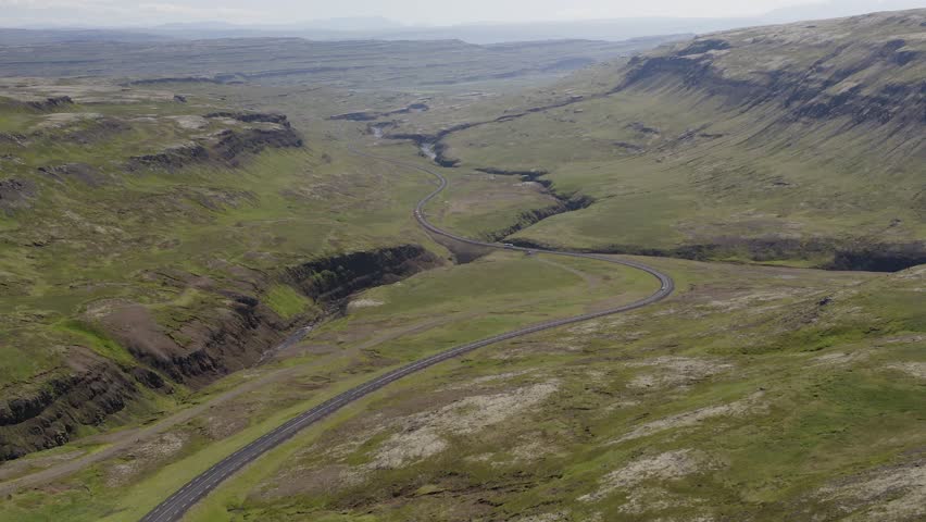 Tilting drone video in Iceland overlooking a beautiful green road winding through the lush valley near Bifrost in Northern Iceland Royalty-Free Stock Footage #3391415693