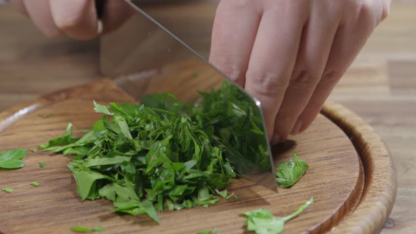 Chef chops parsley on a wooden board with a hatchet knife. Chimichurri preparation Royalty-Free Stock Footage #3391459099