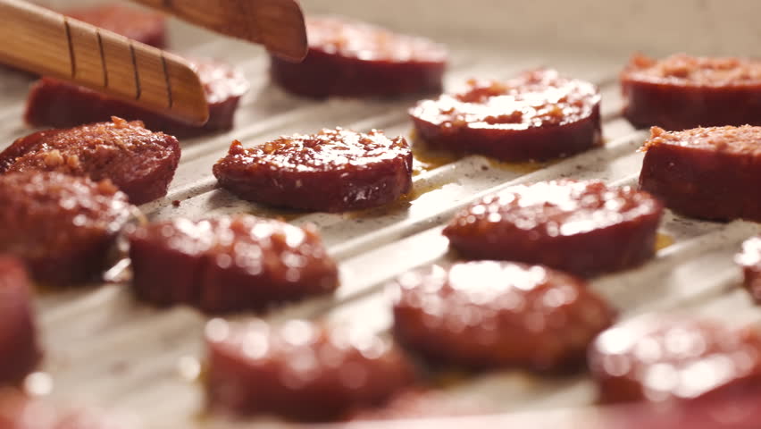 Cooking Turkish Sausage Also Known as Sucuk in Pan. Unrecognizable Person Flipping Sliced Meats to Roast Perfectly. Preparing for Breakfast Close Up Shot Slow Motion. Camera Moving Left to the Right. 