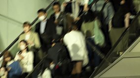 TOKYO, JAPAN - NOV 2023 : Crowd of people on the escalator at night. Shot in busy rush hour. Japanese people, tourists, diversity and lifestyle concept video. Blurred time lapse shot.