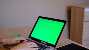4K.Close up woman using smartphone green screen on the table with laptop computer Chromakey. Close up shot of woman's hands holding mobile phone swiping scrolling green screen..