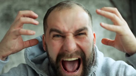 anger, people, emotions, 4K and lifestyle concept - Model released man in studio screaming, smiling and winking at camera. Manifestation rage of man. Slow motion