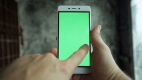 art, people, technologies, 4K and lifestyle concept - Closeup man hand holding and touching phone with green screen vertical