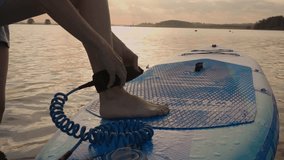 Close up of man puts safety rope on leg before SUP boarding. Male preparation for paddle boarding and water sports. Active and safety healthy lifestyle - Powered by Shutterstock - Get 15% off with code: PIKWIZARD15