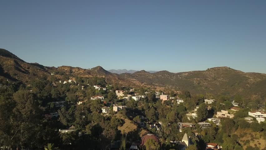 Slow zoom out aerial view of los angeles city hills mountains desert trees water city in background