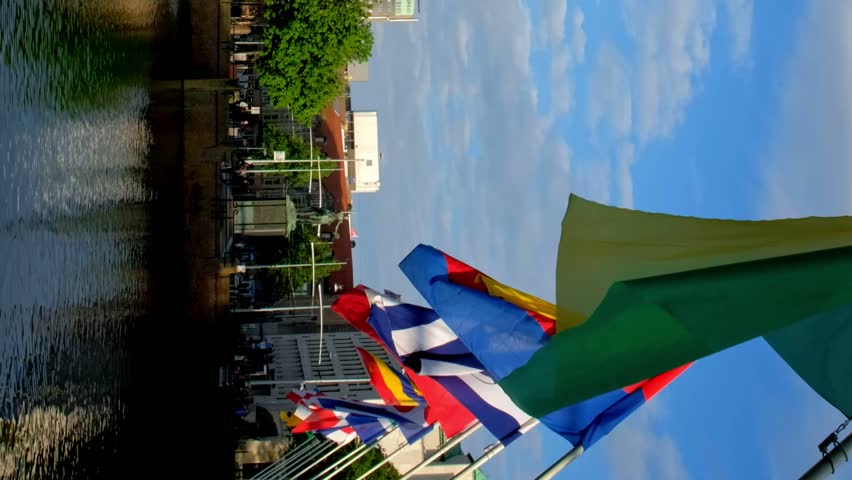 View of the Binnenhof House of Parliament and the Hofvijver lake with downtown skyscrapers in background with flags. The Hague, Netherlands