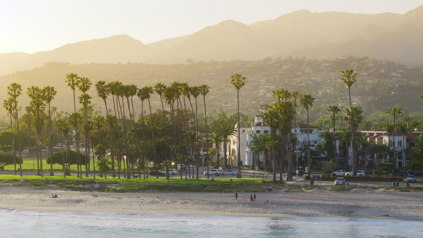 Panoramic view of picturesque landscape of Santa Barbara city shoreline, California, USA. Drone shot of tourists enjoying vacation on the beach. Sunset light falling on the mountain top, 4k footage  Royalty-Free Stock Footage #3391608711