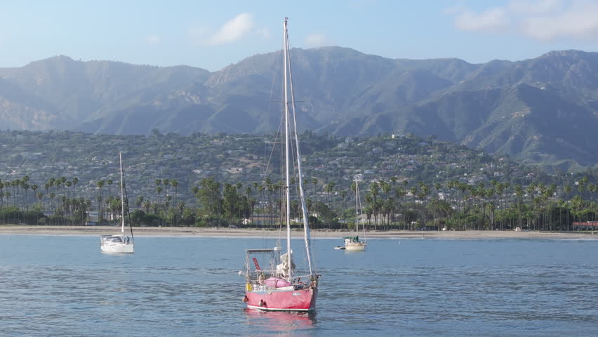 Scenic view from Point Castillo on sailboats sailing in Santa Barbara Harbor, California, USA. Picturesque shot of yachts docked at Pacific coastline. Mountains landscape on background, 4k footage Royalty-Free Stock Footage #3391613295