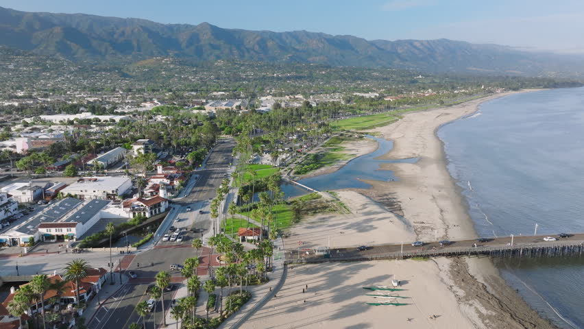 Birds eye view of Santa Barbara shoreline with city skyline, California, USA. Drone flying along resort city surrounded green mountains. Aerial shot of sandy beach located at Pacific Ocean, 4k footage Royalty-Free Stock Footage #3391617409