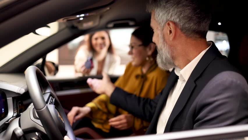Happy mature couple sitting in the brand new car they want to buy and trying them