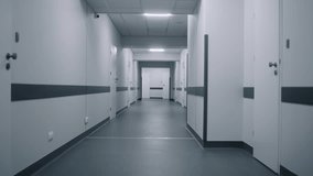 Modern medical center with empty hallway before start of work. Hospital corridor and cabinet doors illuminated by LED lamps. Health care system. Clinic closed on quarantine. Pandemic. Dolly shot. - Powered by Shutterstock - Get 15% off with code: PIKWIZARD15