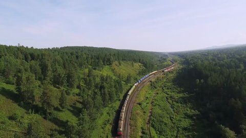 Freight train carries an electric locomotive by two-sided winding Trans Siberian railway with railroad crossing  in the Ural Mountains - Aerial Photography, top view