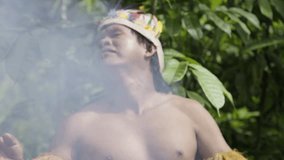 An indigenous man performs a ritual using smoke in the dense forest of Leticia, Amazon, Colombia