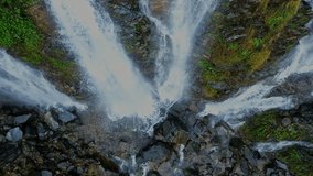 Waterfall flowing on a cliff in the middle of a tropical forest during the rainy season with a large amount of water with an aerial view from a drone.