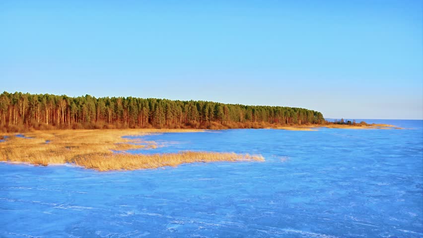 Reflection of the sky in the ice of the lake, super bright colors at golden hour. Aerial Drone Shot.