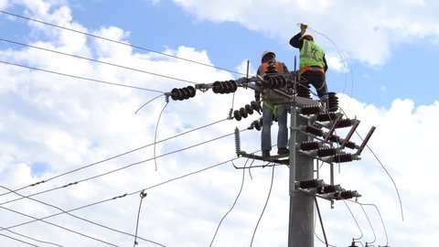men working on a transformer on a electricity power pole