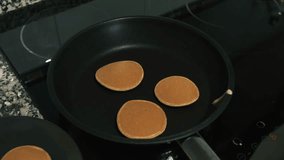 Cooking American-style pancakes for a traditional breakfast - close-up video. Pancake cooking process in a frying pan.  Pancakes with holes. Cooking process. 