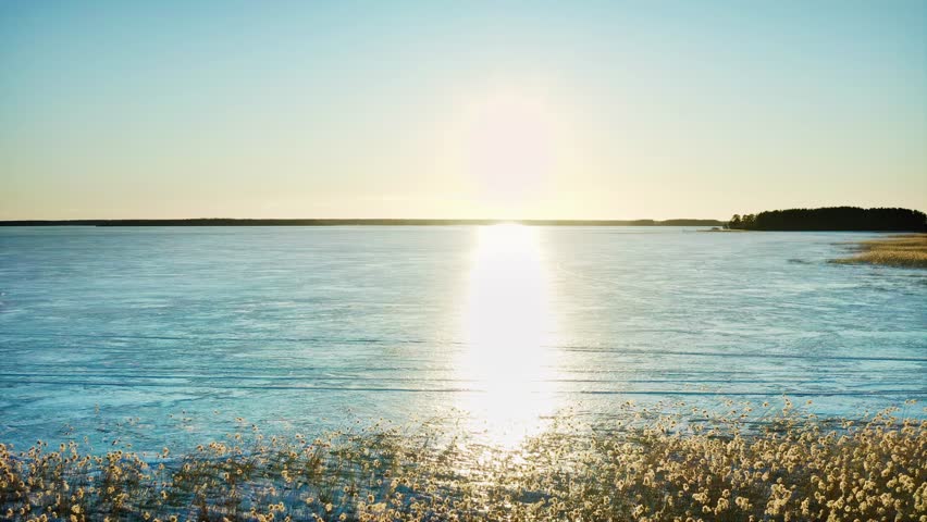 The bright reflection of the sun on the ice of a large body of water. Winter has begun. Aerial Drone Shot.