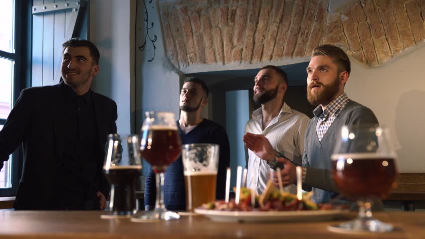 The close-up portrait of the man spending their down time by cheering for their favourite team, doing toasts to its winning and drinking beer in the football bar.