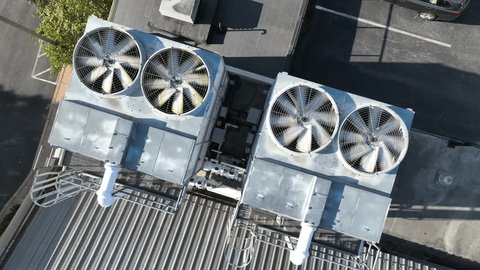 Spinning shot of air conditioning utility unit on roof of industrial building. Top down aerial orbit. Fan rotating as cooling tool. : vidéo de stock