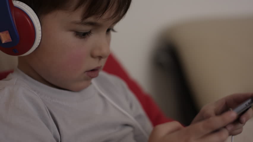 Child Happy Playing Games With Phone. Little Boy With Headphones Playing Video Game on Mobile Phone. Preschooler Plays Video Game On Smartphone. Harm for Mental Kid Health Eyesight Gambling Addiction | Shutterstock HD Video #3391990439