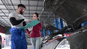 In an auto repair shop, A man professional auto mechanic briefs a female customer about the cost of car repairs and collects payment. - Powered by Shutterstock - Get 15% off with code: PIKWIZARD15