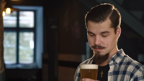 The close-up portrait of the man with brooklyn bartender mustaches drinking beer and wiping the foam out of his mustaches.