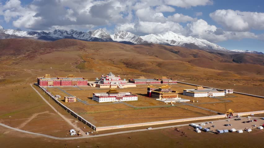 Aerial pullback reveals expanse of white mountains and temples in Tagong grasslands of Sichuan China
