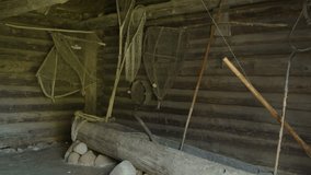 Old narrow wooden fishing boat stands on stones in storage facility, no people. Ancient nets and fishing gear hang on wooden barn wall in authentic village. - Powered by Shutterstock - Get 15% off with code: PIKWIZARD15