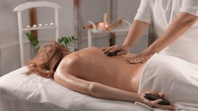 How Hot Stone Massage Revitalizes the Body and Improves Your Physical Condition. The video captures effective moments effect hot stones on different parts body in beauty and body care massage salon
