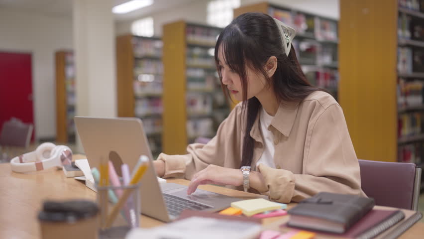 young asian student woman doing lesson exam at college library
