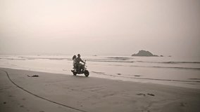 Romantic couple ride motorbike on ocean beach on a date at sunrise. Lovers travel by motorcycle on coastline along water edge with reflection, splashes. Girlfriend hugs her boyfriend, spreads arms. - Powered by Shutterstock - Get 15% off with code: PIKWIZARD15