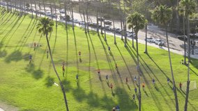 Aerial shot of male athletes playing football on green field of Santa Barbara, California, USA. Birds eye view of local men exercising with soccer ball outdoors. Players training outdoors, 4k footage 