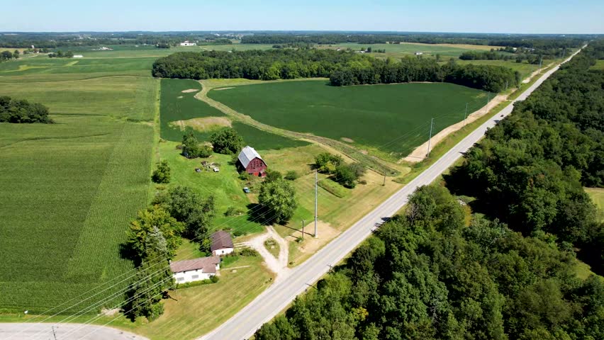 Flying over mid west farm country with red barn, fields and long straight road
