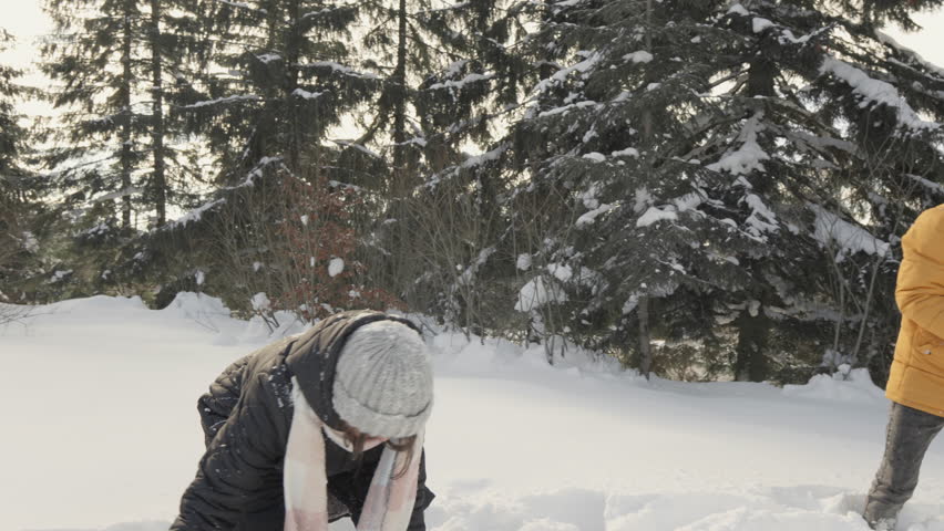 Energetic couple playing in the snow, throwing snowballs, enjoying the joyful moments of the winter game. They have fun in winter in nature, relax and have fun.