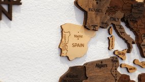 Video capture of a hand positioning a paper airplane pin on Madrid, symbolizing wanderlust and educational interest in Spain's geography.